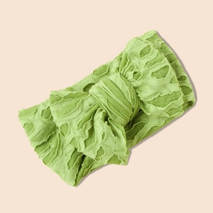 Détail d'un bandeau bébé vert clair en maille extensible avec un grand nœud texturé