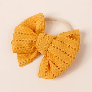 Macro detail of yellow lace mesh bow headband featuring intricate hollow textures