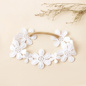 Détail de broderie de fleurs en dentelle blanche sur un bandeau souple en nylon pour bébés