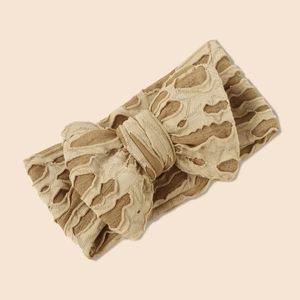 Détail d'un bandeau en maille pour bébé avec texture popcorn et nœud papillon ajouré