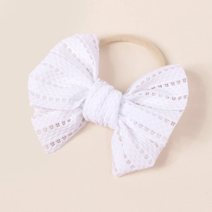 Close-up of baby headband featuring a large white lace bow with delicate hollowed texture