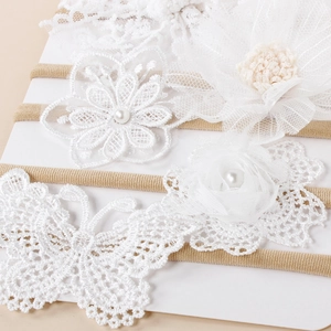 Détail d'un bandeau bébé en dentelle blanche avec broderies florales et perles