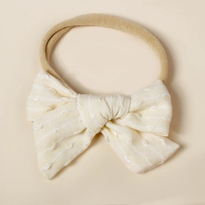 Detailed macro shot of a soft nylon baby headband with a cream knitted striped bow