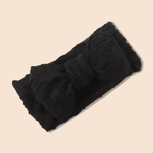 Détail d'un bandeau large noir extensible pour bébé avec texture ondulée et nœud central
