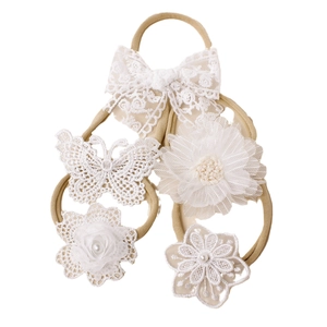 Détail de cinq bandeaux pour bébé en dentelle blanche avec motifs floraux et nœuds brodés