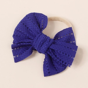 Detail of baby headband featuring dark blue hollow lace bow and nude elastic nylon band