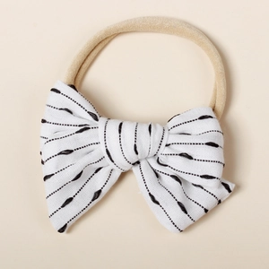 Close-up of soft nylon baby headband with white striped bow and delicate embroidery texture