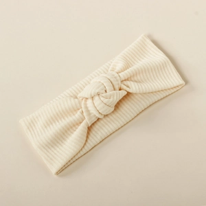 Detail of soft ribbed knit cream baby headband with stylish twist knot design