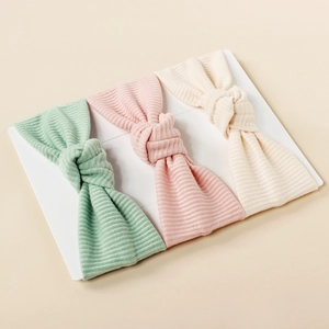 Three-pack ribbed knit baby headbands in soft green, pink, and cream with knot detail
