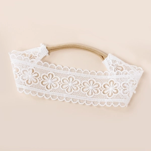 Détail de la broderie florale blanche sur le bandeau en nylon doux pour bébé