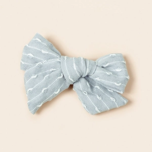 Détail d'un nœud papillon bleu clair avec broderie blanche et texture en tissu tissé