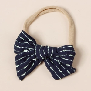 Detail of baby headband with navy striped bow and soft skin-tone elastic nylon strap