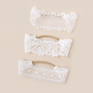 Détail de trois bandeaux bébé en dentelle blanche avec des bandes en nylon souple