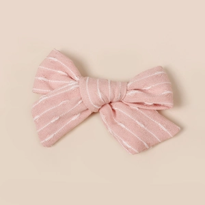 Gros plan d'une barrette nœud à rayures roses et blanches montrant la texture du tissu