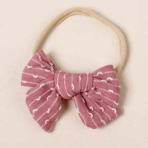 Detail of pink striped cotton bow with soft beige nylon headband for infants and babies