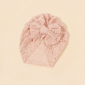 Detail view of pink lace baby turban with floral texture and large soft bow design
