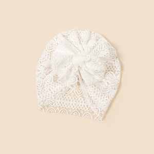 Close-up of white lace turban beanie for babies with a large decorative bow