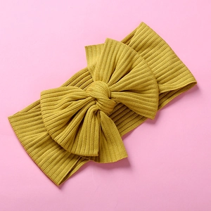 Detail of bright yellow ribbed knit baby headband with a large decorative 3D bow accent