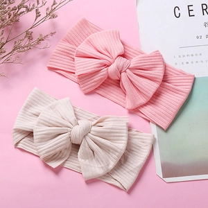 Detail of pink and beige ribbed knit headbands with large 3D bows for baby girls