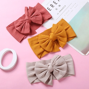 Three-piece set of knitted baby headbands with large bows in pink, yellow, and beige