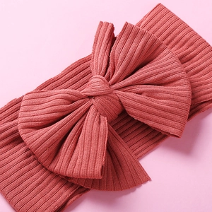 Elastic ribbed knit baby headband with a large textured bow in dusty rose color