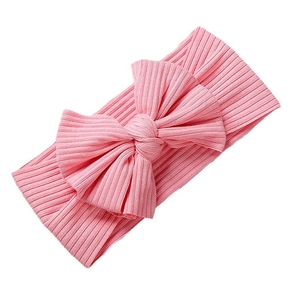 Pink knitted ribbed headband for babies with a large decorative bow on a white background