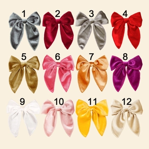 Flat lay of twelve velvet bow hair clips for girls in various vibrant colors