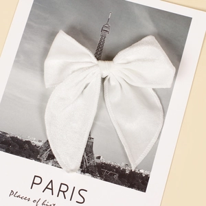 Detail of a large white velvet bow hair clip with long ribbons on a vintage card