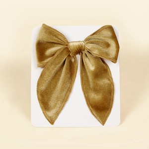 Detail of a golden velvet swallowtail bow hair clip on a white display card backing