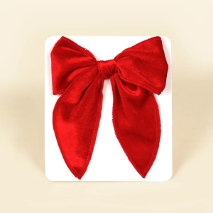 Close-up of a large red velvet bow hair clip with textured fabric and sewing detail