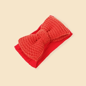 Detail of red knitted bow headband for infants showing soft texture and ribbed pattern