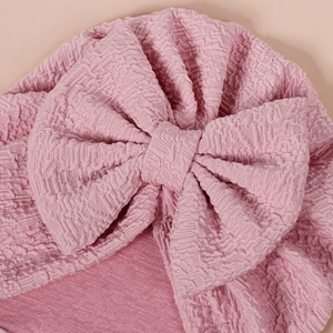 Pink waffle knit baby turban hat with a large bow detail for newborns and infants