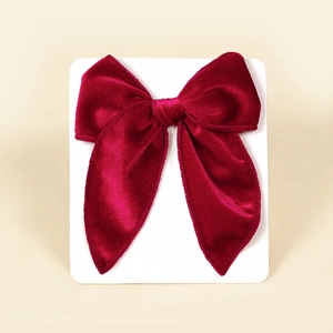 Macro shot of deep red velvet swallowtail bow hair clip showing luxury fabric texture