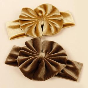 Détail de bandeaux à nœud en velours or et marron montrant la texture douce et élastique