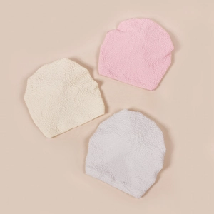 Close-up of bubble texture knit newborn hats with bows in pink, beige and white