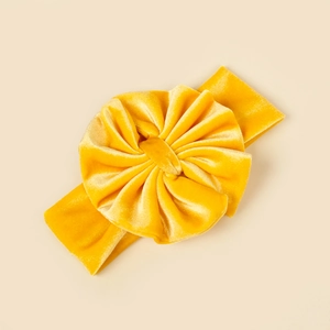 Détail d'un bandeau bébé en velours jaune vif avec un grand nœud floral plissé élégant