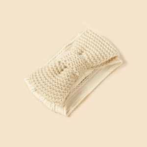 Detailed macro view of cream knitted bow headband with soft elastic ribbed texture