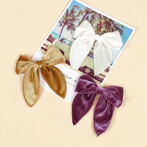 Three elegant velvet long-tail bow hair clips in cream, gold, and purple colors
