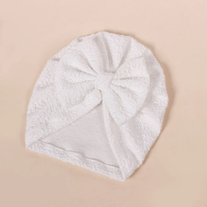 Detailed view of white baby turban with textured bubble fabric and large bow decoration