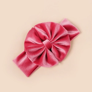 Détail de la texture velours sur le bandeau bébé rose avec un grand nœud plissé