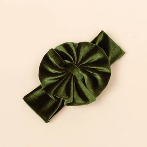 Détail d'un bandeau pour bébé en velours avec un grand nœud plissé vert foncé