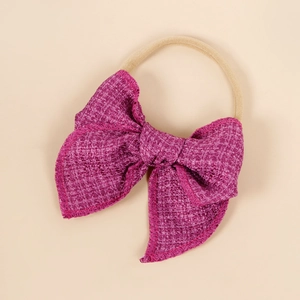 Détail du nœud en tissu violet foncé sur un bandeau doux en nylon pour bébé