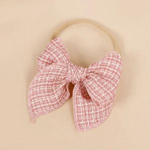 Détail du nœud en tweed à carreaux rose et blanc sur un bandeau élastique en nylon