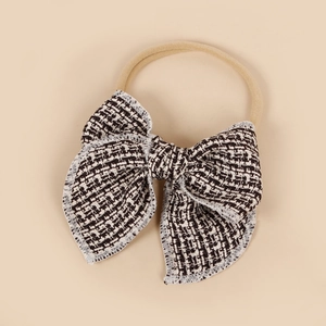 Détail du bandeau bébé en nylon souple avec un élégant nœud en tweed noir et blanc
