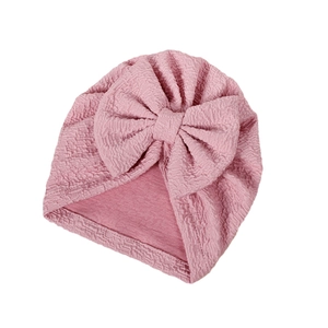 Pink bubble fabric baby turban hat featuring a large decorative bow for newborns