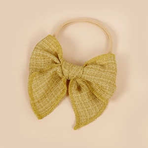 Détail du nœud en tissu tweed jaune moutarde et du bandeau élastique rose doux pour bébé