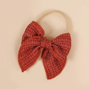 Détail d'un nœud en tissu rouge sur un bandeau élastique doux pour bébé en nylon