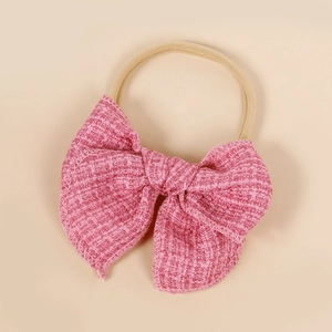 Détail du nœud en tweed rose sur bandeau bébé en nylon doux à haute élasticité