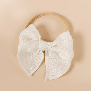 Détail d'un bandeau souple pour bébé en nylon avec un grand nœud en tissu blanc texturé