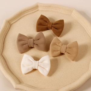 Detailed view of four velvet fabric hair bows in earth tones on an octagonal tray